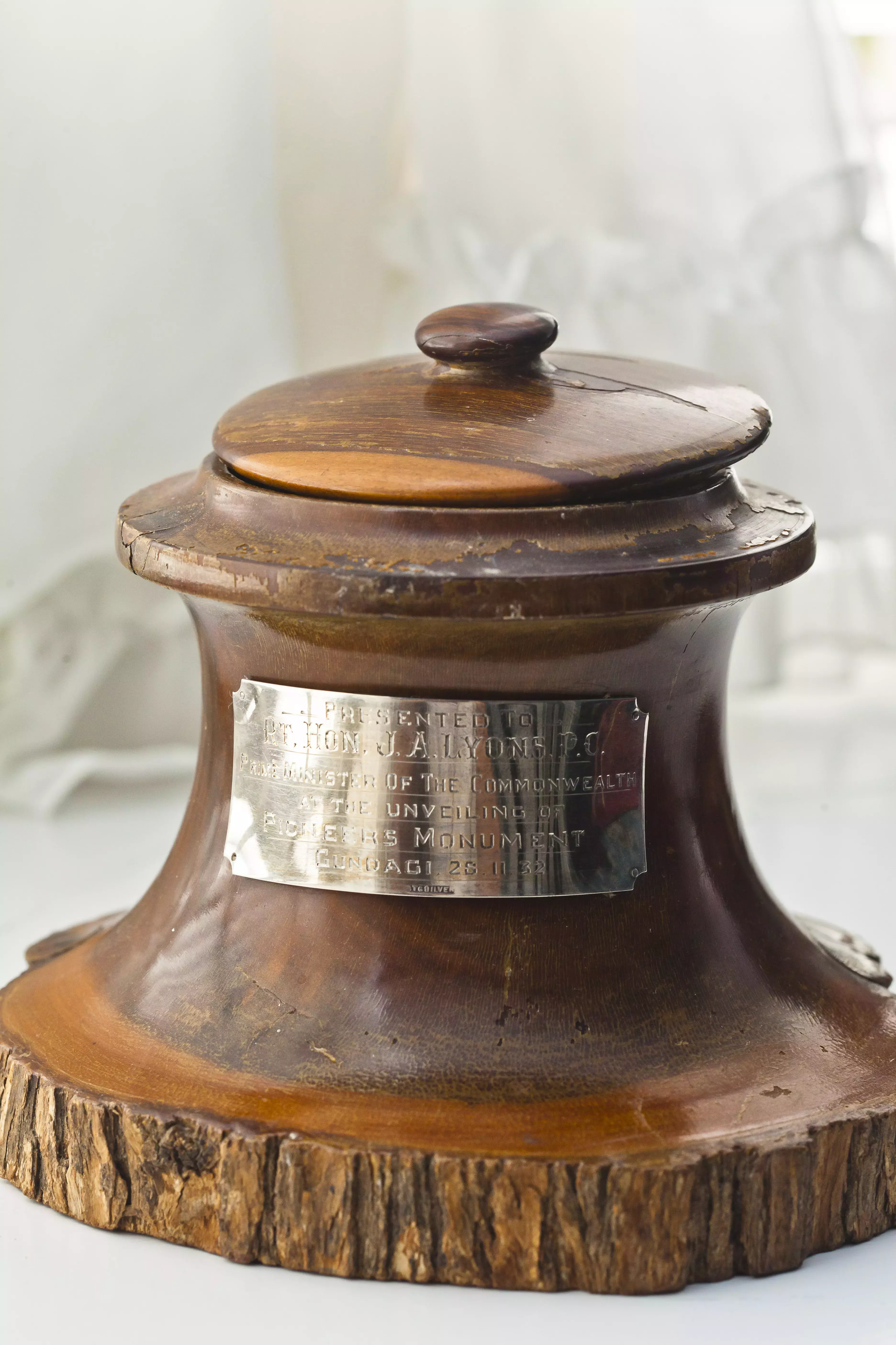 A carved wooden bowl with a lid and an engraved plaque. 